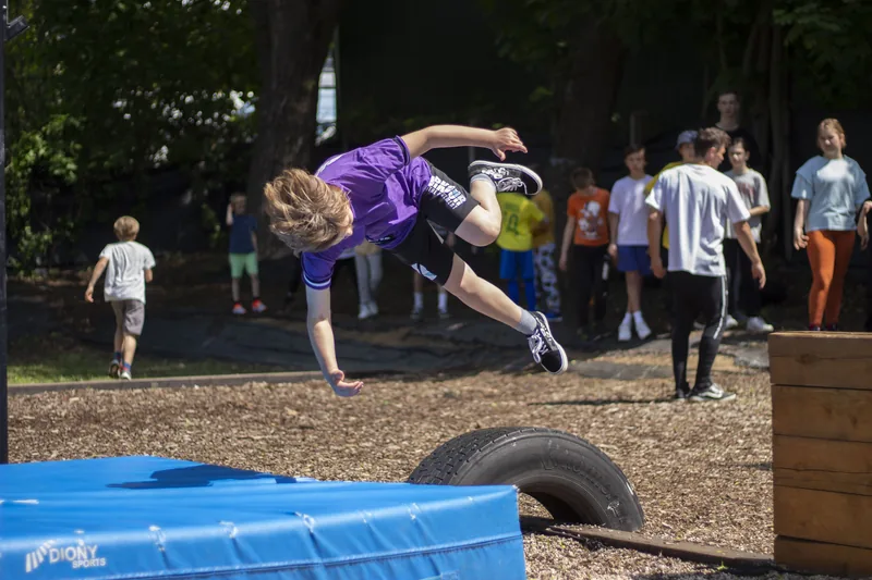 Chlapec v skoku počas detského tréningu parkouru vonku